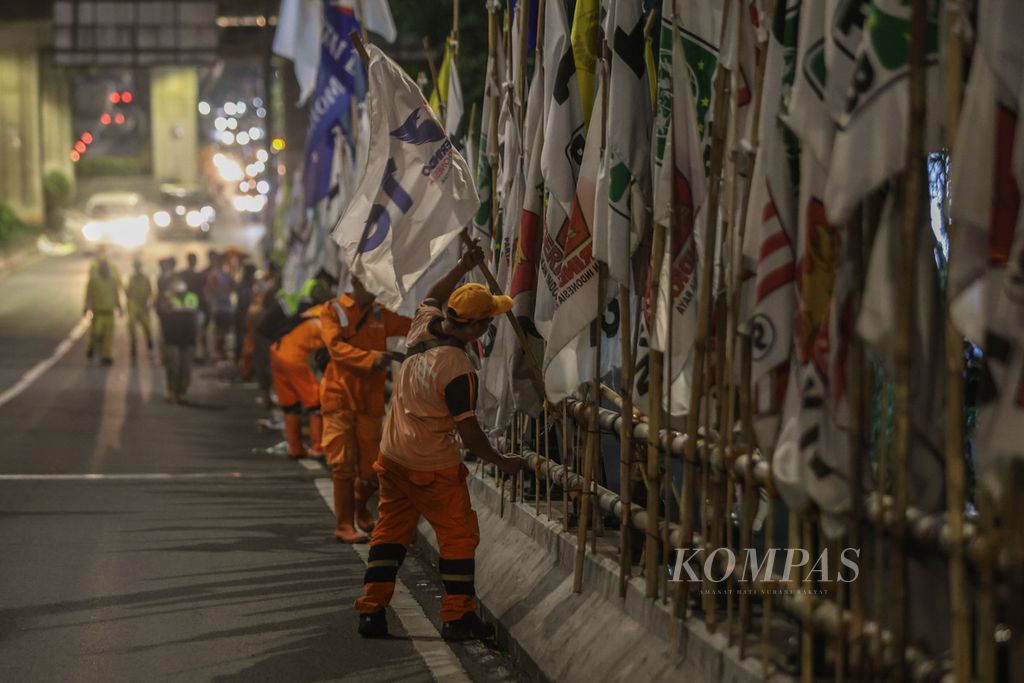 Petugas PPSU menertibkan alat peraga kampanye peserta Pemilu 2024 di Jalan Kapten Tendean, Jakarta, Minggu (11/2/2024).