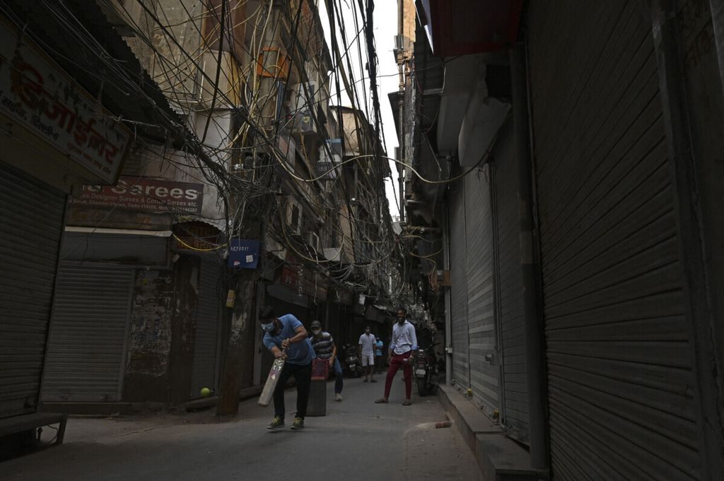 A number of young people play cricket on the street when shops along the road are closed due to the lockdown policy in New Delhi, India, Wednesday (5/5/2021). The Indian government extended the lockdown policy to control the transmission of Covid-19.