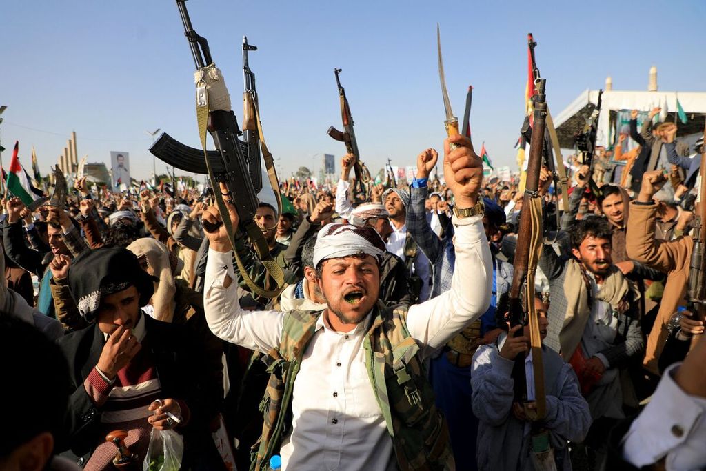 Anggota kelompok Houthi mengacungkan senjata mereka saat melakukan protes menyusul serangan pasukan AS dan Inggris, di ibu kota Sanaa, Yaman, yang dikuasai Houthi, Jumat (12/1/2024). 