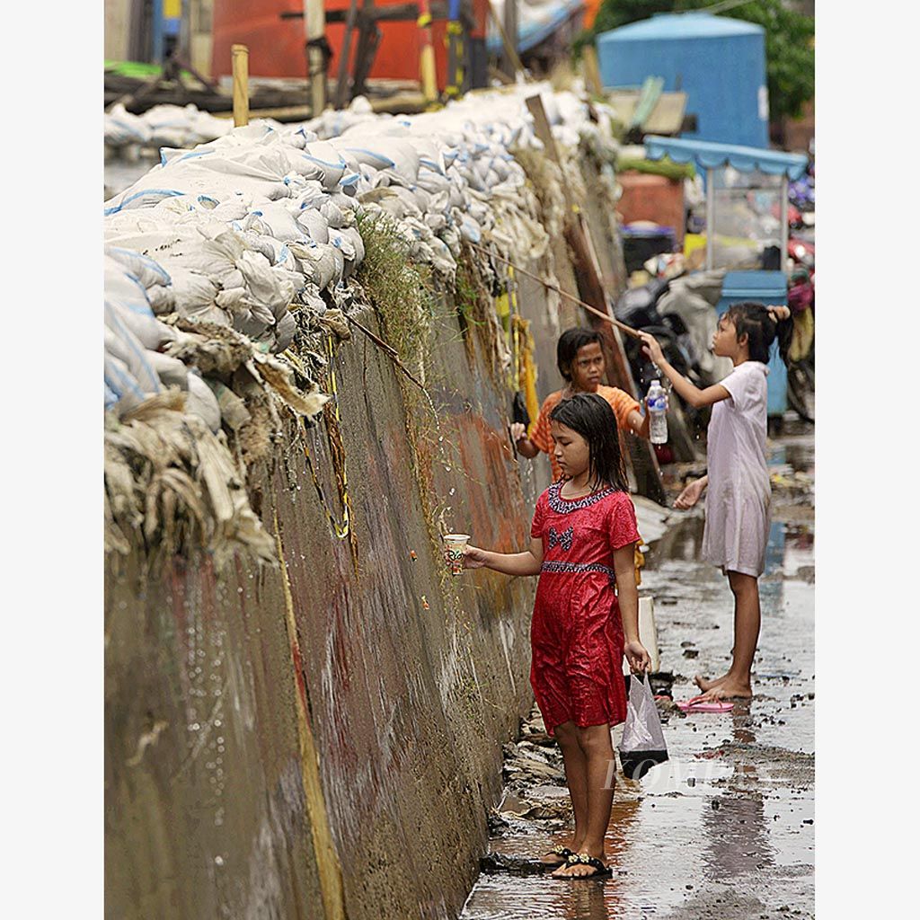 Anak-anak  bermain di sekitar tanggul penahan limpasan air laut (fase A NCICD) masuk ke permukiman warga di Muara Baru, Jakarta, Selasa (5/12). 