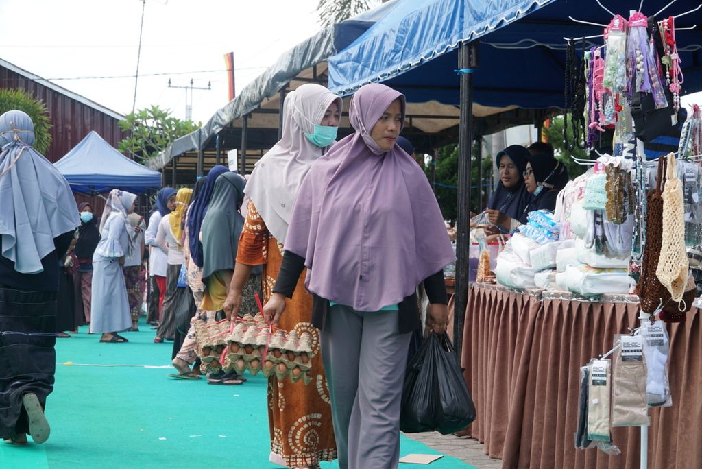 Warga menjinjing telur dan minyak goreng yang dibeli dalam pasar murah yang digelar Dinas Perdagangan Kota Padang di halaman Kantor Camat Kuranji, Padang, Sumatera Barat, Senin (17/1/2022). 