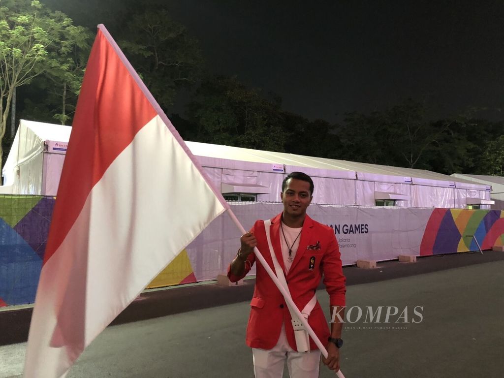 Atlet renang Indonesia, I Gede Siman Sudartawa, yang bertindak sebagai pembawa bendera Merah Putih pada saat defile dalam acara pembukaan Asian Games 2018, Sabtu (18/8/2018).