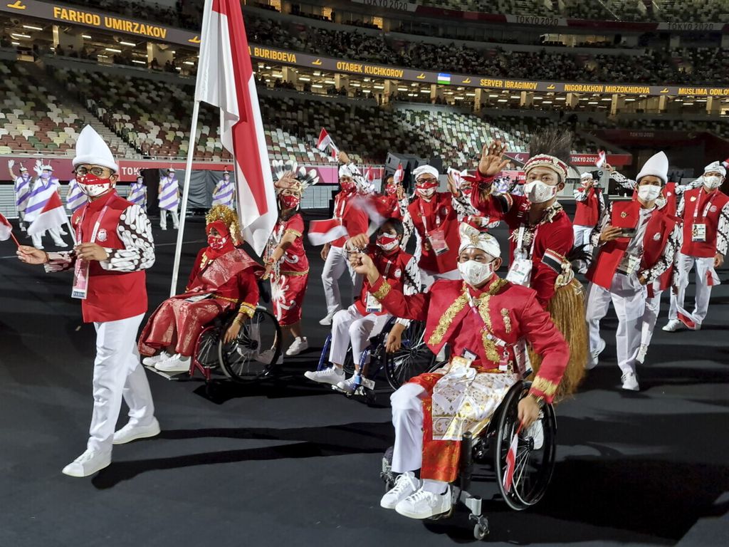 Kontingen Indonesia melintas di Stadion Olimpiade Tokyo, Jepang, saat defile atlet di pembukaan Paralimpiade Tokyo 2020, Selasa (24/8/2021). Total jumlah kontingen Indonesia di Paralimpiade Tokyo 2020, sebanyak 60 orang, terdiri dari atlet, ofisial, tim pendukung, dan logistik. Atlet Indonesia akan berlaga di cabang atletik, angkat berat, menembak, bulu tangkis, tenis meja, sepeda, dan renang. Paralimpiade melombakan 539 nomor dari 22 cabang olahraga yang diikuti sekitar 4.400 atlet pada 24 Agustus-5 September.