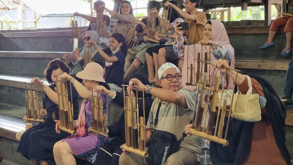 Sejumlah pengunjung memainkan angklung dalam pertunjukan Libur Lebaran 2023 di Saung Angklung Udjo, Kota Bandung, Jawa Barat, Selasa (25/4/2023).