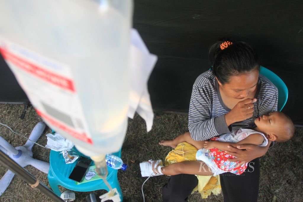 Bayi perempuan berusia 16 bulan, Baiq Adiba Shaqeena, tergolek lemas akibat terjangkit diare dalam pelukan sang ibu, SIti Aisyah, di dalam tenda kesehatan Puskesmas Pemenang, Kabupaten Lombok Utara, Nusa Tenggara Barat, Minggu (26/8/2018). 