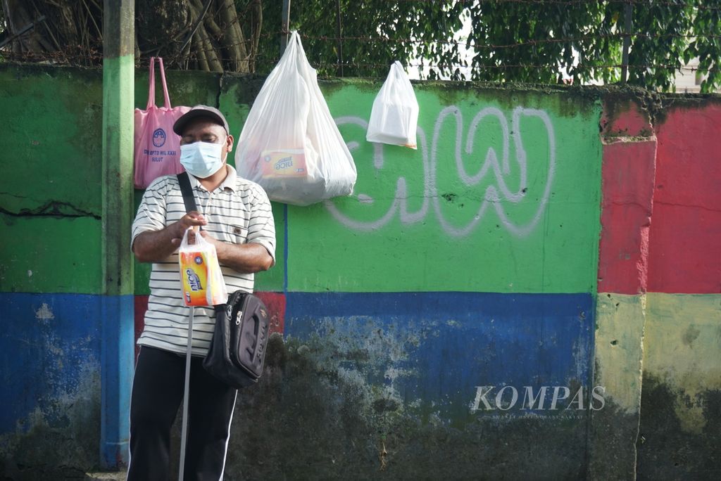 Simon Pare (47) berjualan tisu, Rabu (20/4/2022), di Jalan Sam Ratulangi 3, Wenang Utara, Manado, Sulawesi Utara. Ia adalah satu dari 69 difabel netra di Manado yang berjualan di tepi jalan raya karena kesulitan mendapatkan pekerjaan.