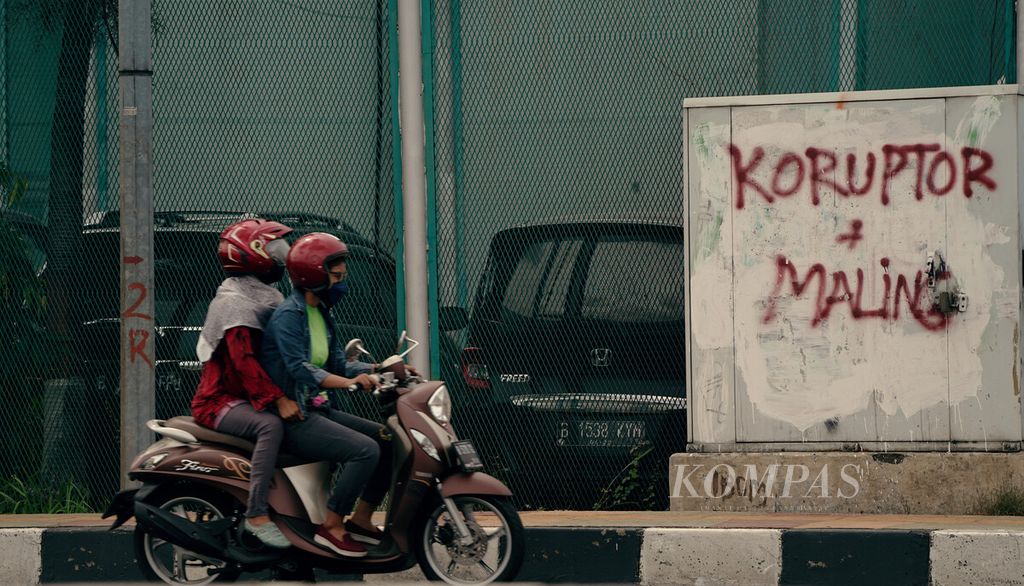 Pengendara motor melintasi coretan kemuakan terhadap koruptor di depan Lembaga Pemasyarakatan Kelas I Cipinang, Jakarta Timur, Jumat (19/11/2021). 