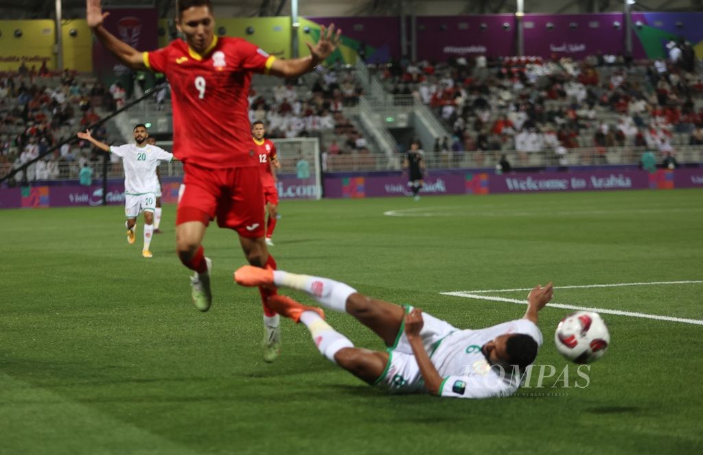 Pemain Kirgistan, Ernist Batyrkanov (kiri), menghindari pemain Oman, Ahmed Al Khamisi, yang terjatuh pada pertandingan terakhir fase Grup F Piala Asia 2023 di Stadion Abdullah bin Khalifa, Doha, Qatar, Kamis (27/1/2024). Kirgistan menahan imbang Oman dengan skor 1-1.
