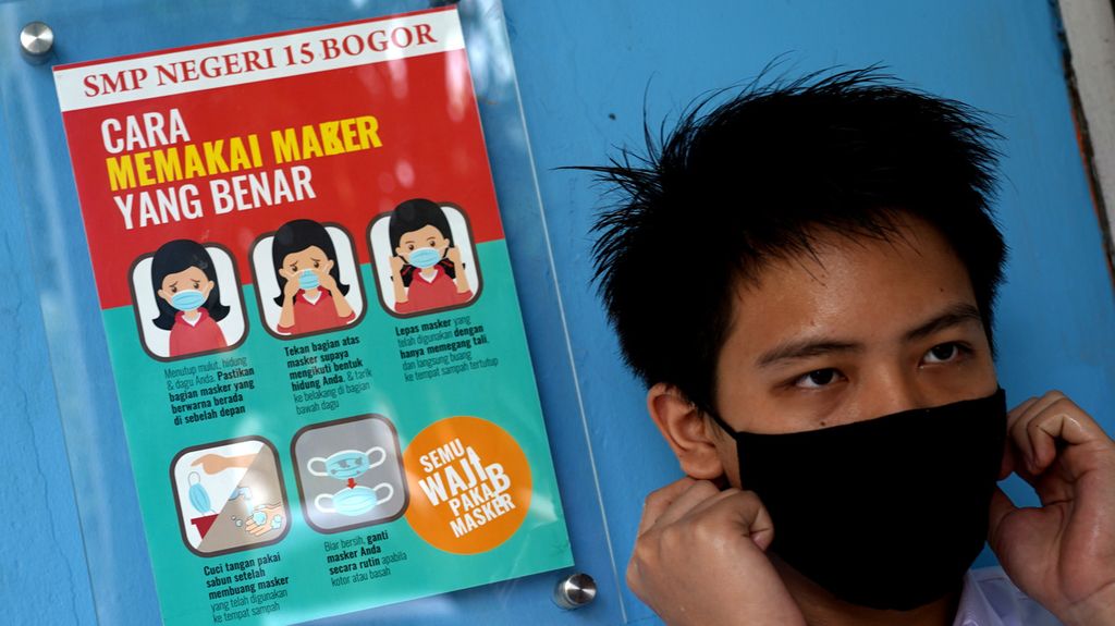 Dimas (13), siswa kelas VII SMP Negeri 15 Kota Bogor, Jawa Barat, memeriksa penggunaan maskernya ketika pelaksanaan uji coba pembelajaran tatap muka, Senin (31/5/2021). 