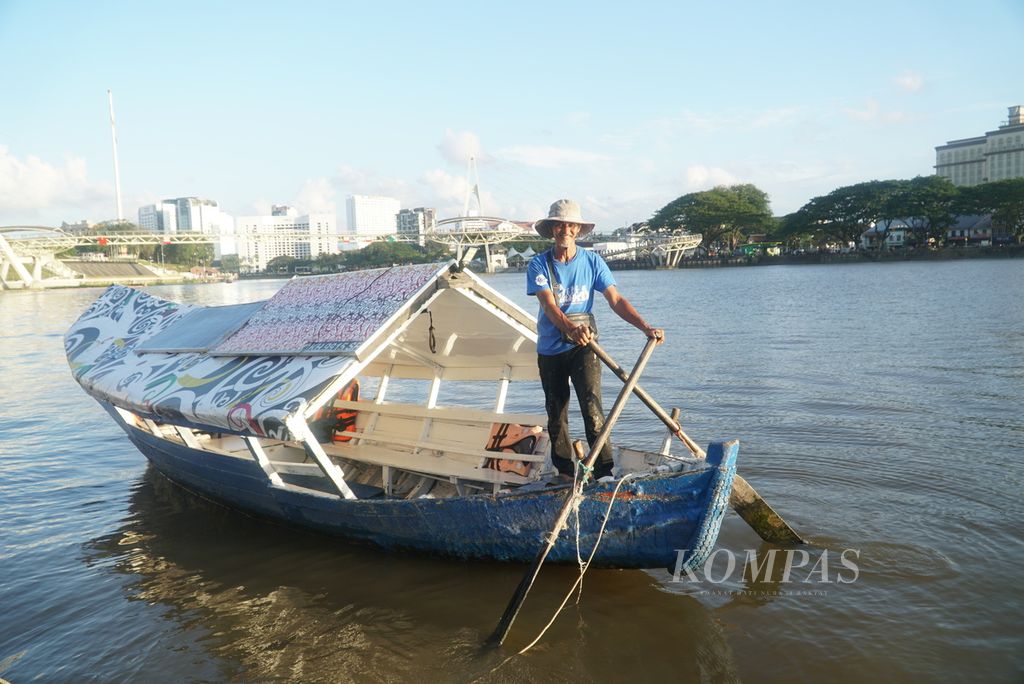 A man carries a mining boat on the Sarawak River, Kuching city, Sarawak, Malaysia, Saturday (24/2/2024) afternoon.