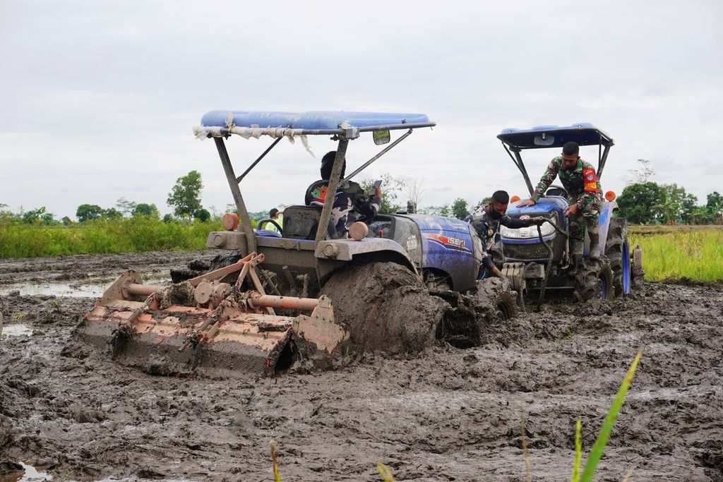 Salah satu traktor yang digunakan anggota TNI dalam membajak sawah sempat tersendat lumpur dan harus ditarik traktor lainnya di Desa Gadabung, Kabupaten Pulang Pisau, Kalimantan Tengah, Sabtu (10/10/2020).