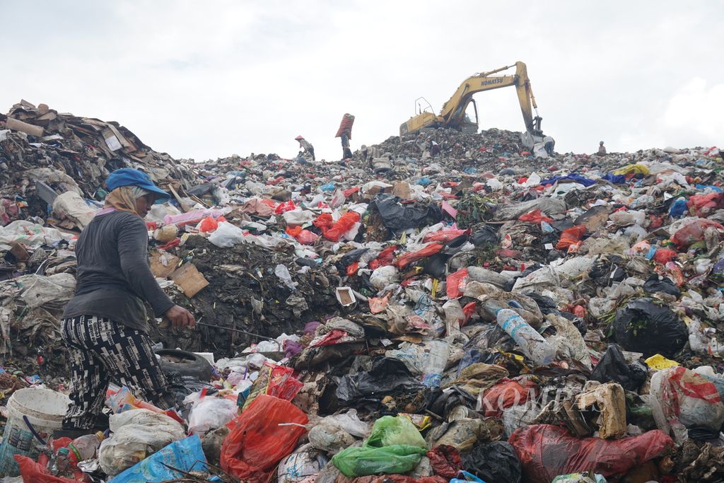Petugas sampah bekerja di kaki gunungan sampah, Jumat (18/9/2020), di Tempat Pembuangan Akhir Sumompo, Manado, Sulawesi Utara.