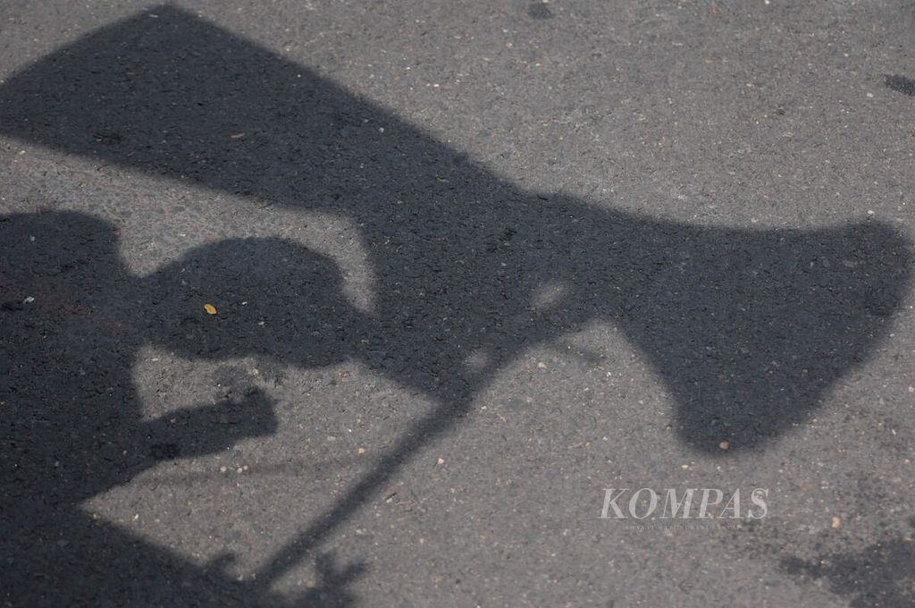 The shadow of activists is cast as they give a speech to commemorate Labor Day on Pahlawan Street, Semarang City, Central Java, on Wednesday, May 1, 2024. Workers who were on holiday still carried out a solidarity action to demand their welfare and push for changes in government policies related to several laws that are not in their favor.