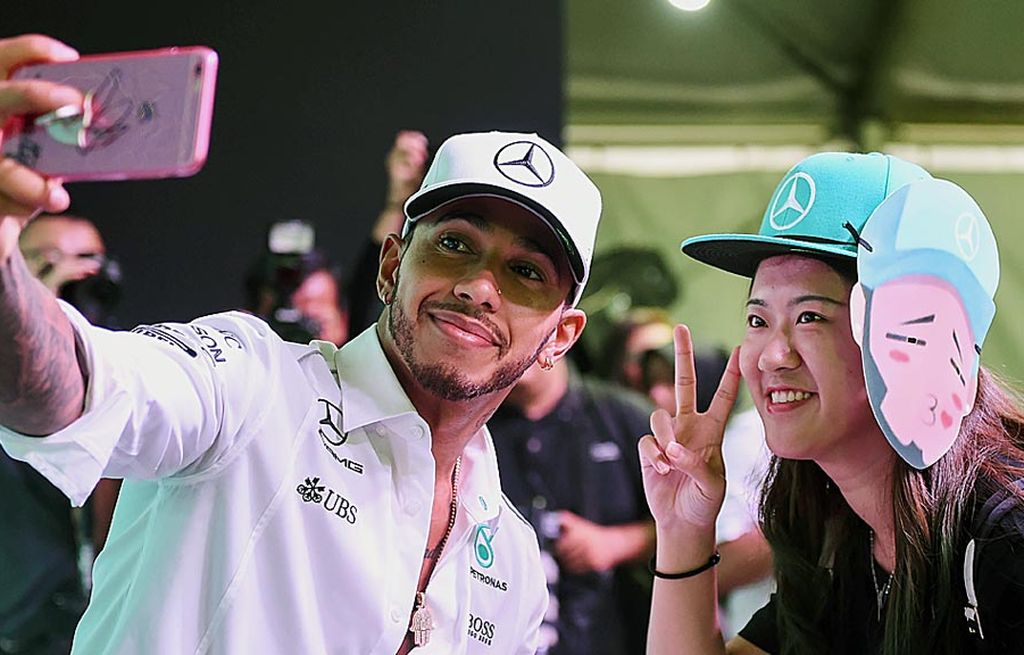 Pebalap tim Mercedes,   Lewis Hamilton (kiri), berswafoto dengan salah satu penggemarnya pada sesi pertemuan dengan fans di Kuala Lumpur, Rabu (27/9). Hamilton bersiap menjelang balapan Formula 1 seri Malaysia di Sirkuit Sepang, Minggu (1/10).