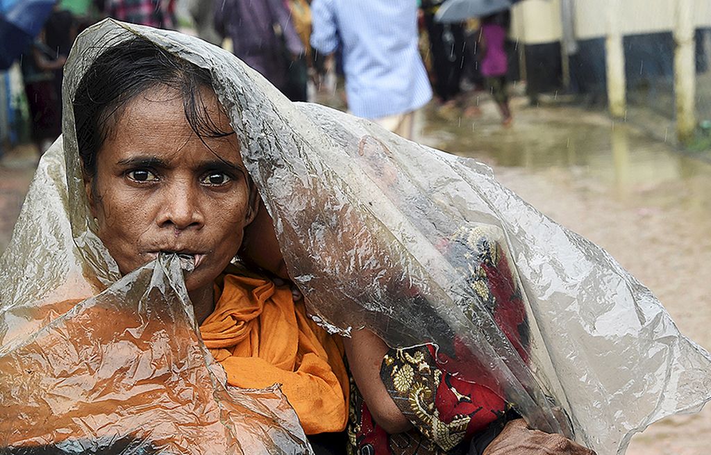 Warga Rohingya menggunakan selembar plastik untuk melindungi diri dari hujan di kamp pengungsi Leda, dekat Teknaf, Banglades, Selasa (19/9). Penasihat Negara Myanmar Aung San Suu Kyi  mengecam kekerasan di Rakhine dan berkomitmen memulihkan stabilitas serta supremasi hukum di wilayah itu.