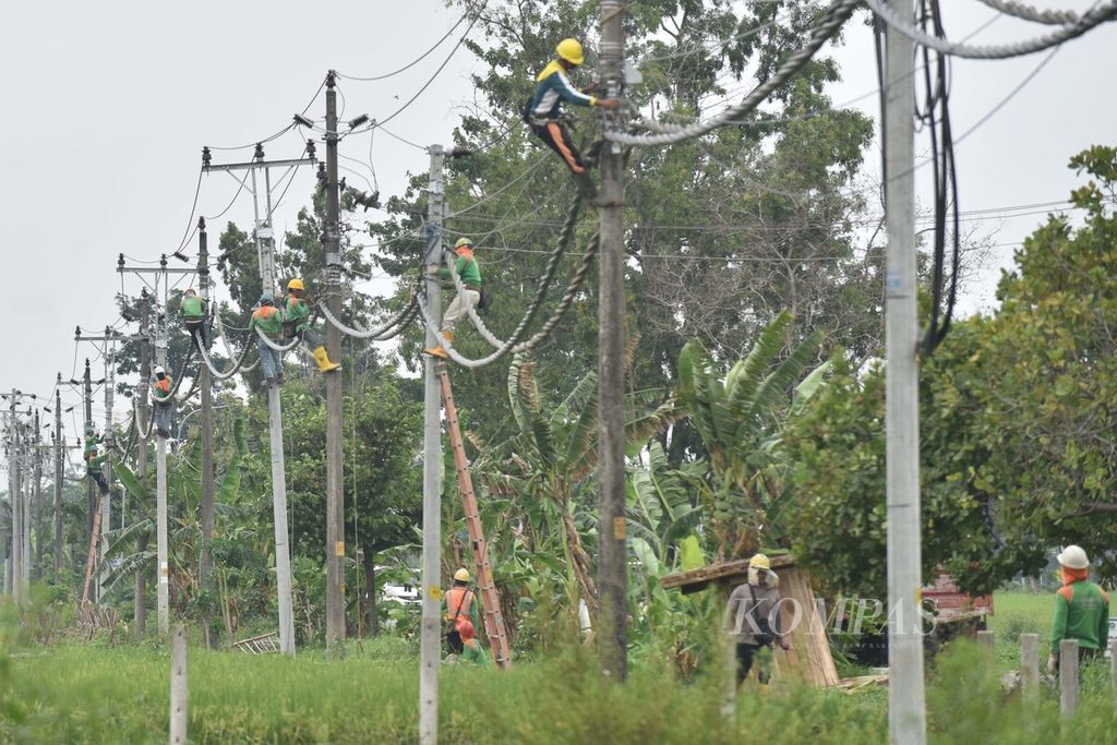 Petugas PLN menyelesaikan pemasangan saluran kabel udara tegangan menengah (SKUTM) di Desa Bangak, Banyudono, Boyolali, Jawa Tengah, Minggu (29/12/2019). 
