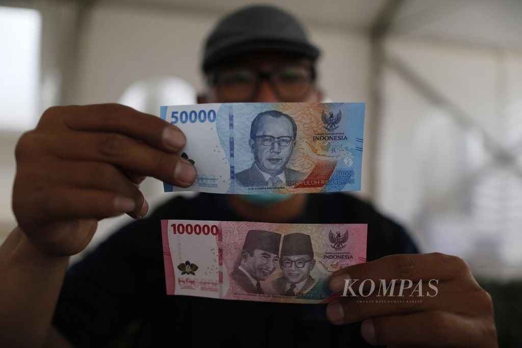 Warga menunjukkan uang rupiah kertas emisi tahun 2022 pecahan Rp 100.000 dan Rp 50.000 dalam Festival Rupiah Berdaulat yang diadakan Bank Indonesia di GOR Basket Gelora Bung Karno, Senayan, Jakarta, Jumat (19/8/2022). 