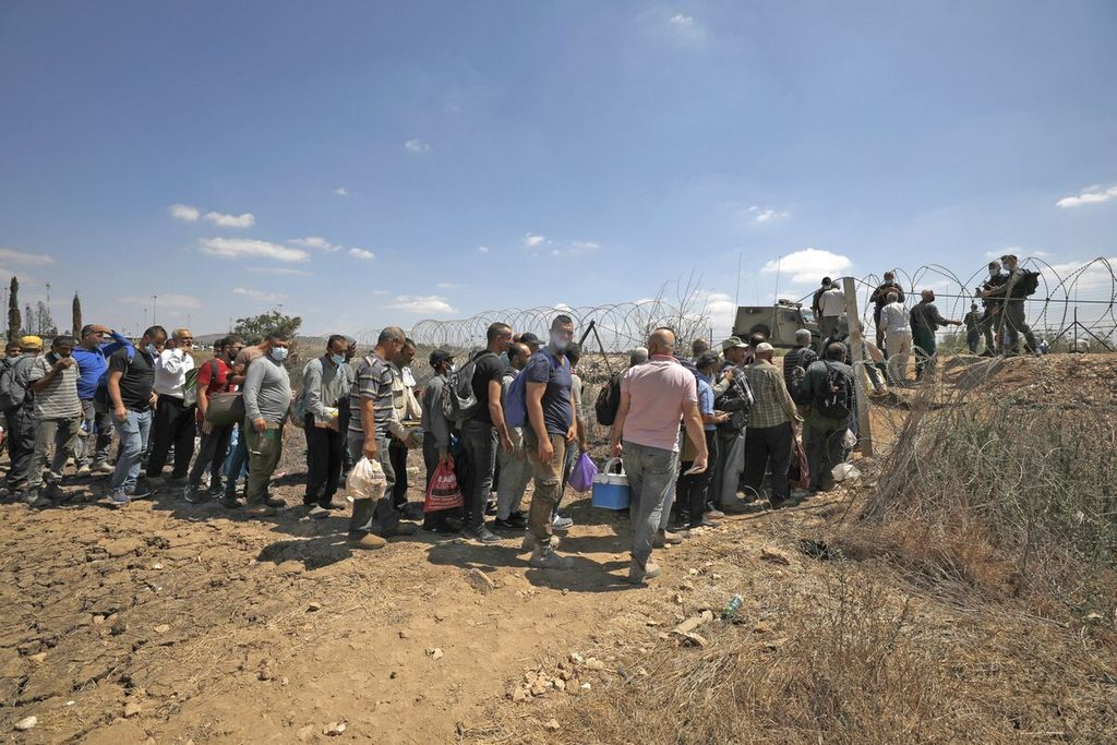 Para pekerja warga Palestina, yang bekerja di Israel, antre untuk melewati pemeriksaan keamanan di desa Muqeibila dekat kota Jenin di Tepi Barat, Senin (6/9/2021). Pelarian enam tahanan warga Palestina melalui terowongan yang digali di dalam penjara memicu pencarian besar-besaran oleh otoritas keamanan Israel. AFP/JALAA MAREY