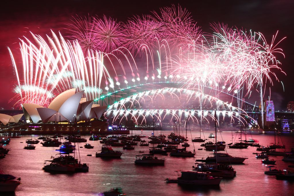 Kembang api malam Tahun Baru menerangi langit di atas Sydney Opera House (kiri) dan Harbour Bridge saat pertunjukan kembang api di Sydney, Australia, pada 1 Januari 2023. 