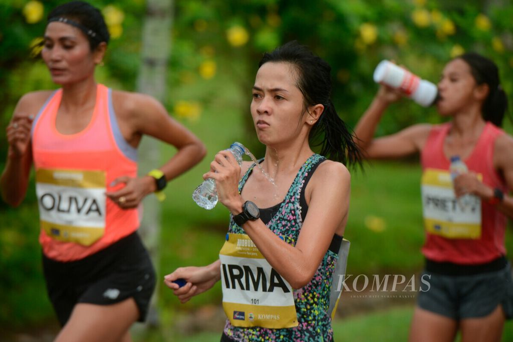 Irma mendinginkan tubuhnya dengan air mineral saat ditempel ketat dua pelari lain pada Borobudur Marathon 2020 di kawasan Candi Borobudur, Kabupaten Magelang, Jawa Tengah, Minggu (14/11/2020). Gelaran Borobudur Marathon ini diikuti sembilan atlet pelari putri.