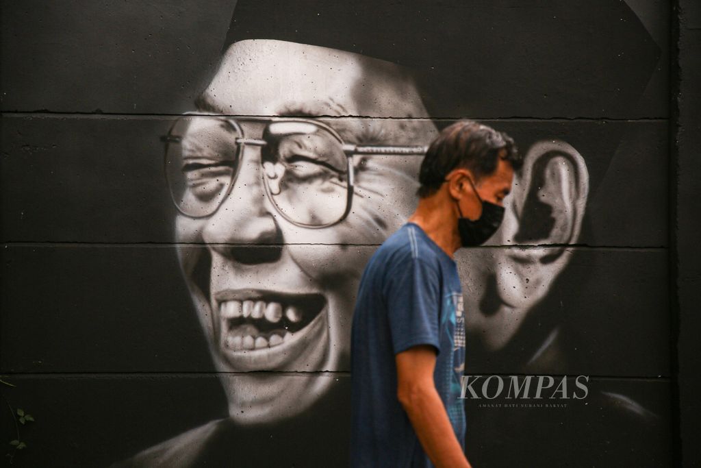 Warga melintasi mural wajah Presiden ke-4 KH Abdurrahman Wahid atau akrab disapa Gus Dur di Jalan H Baan, Poris Plawad Indah, Kota Tangerang, Banten, Minggu (16/5/2021). Sosok Gus Dur terkenal dengan toleransi dan pluralismenya. 