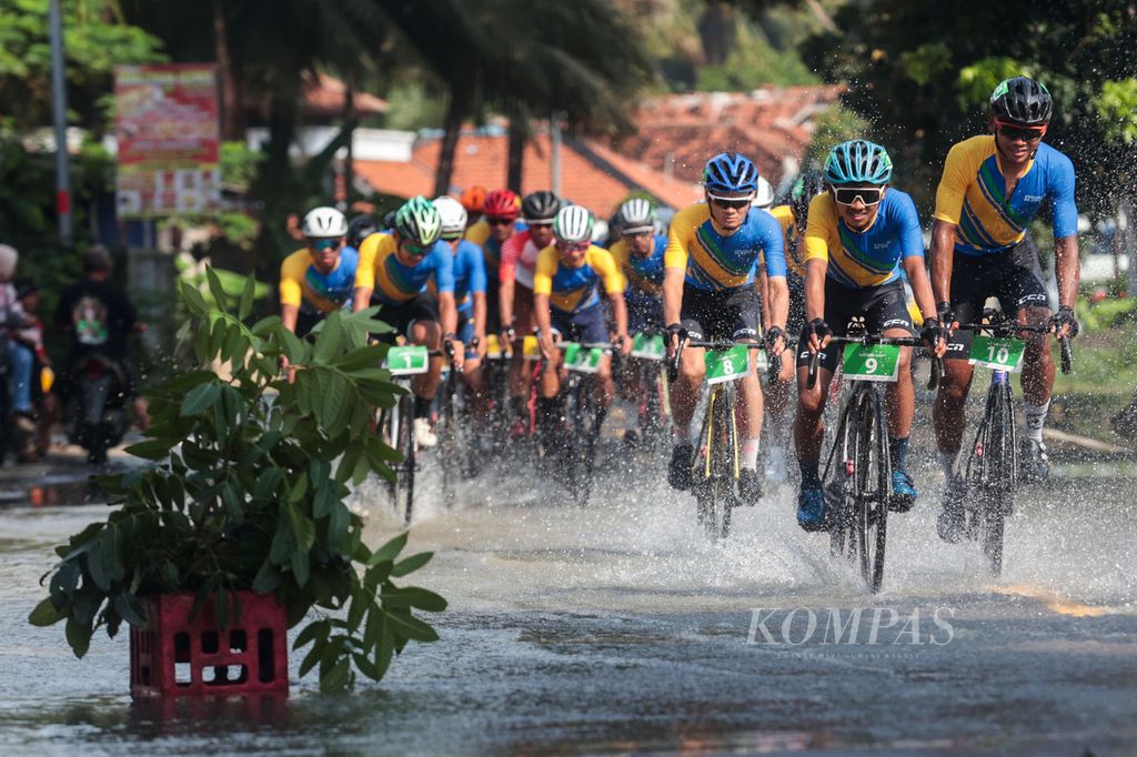 Pebalap menerjang genangan air saat melintasi Cikawungading, Tasikmalaya, Jawa Barat, pada etape kedua Cycling de Jabar 2023, Minggu (9/7/2023). 