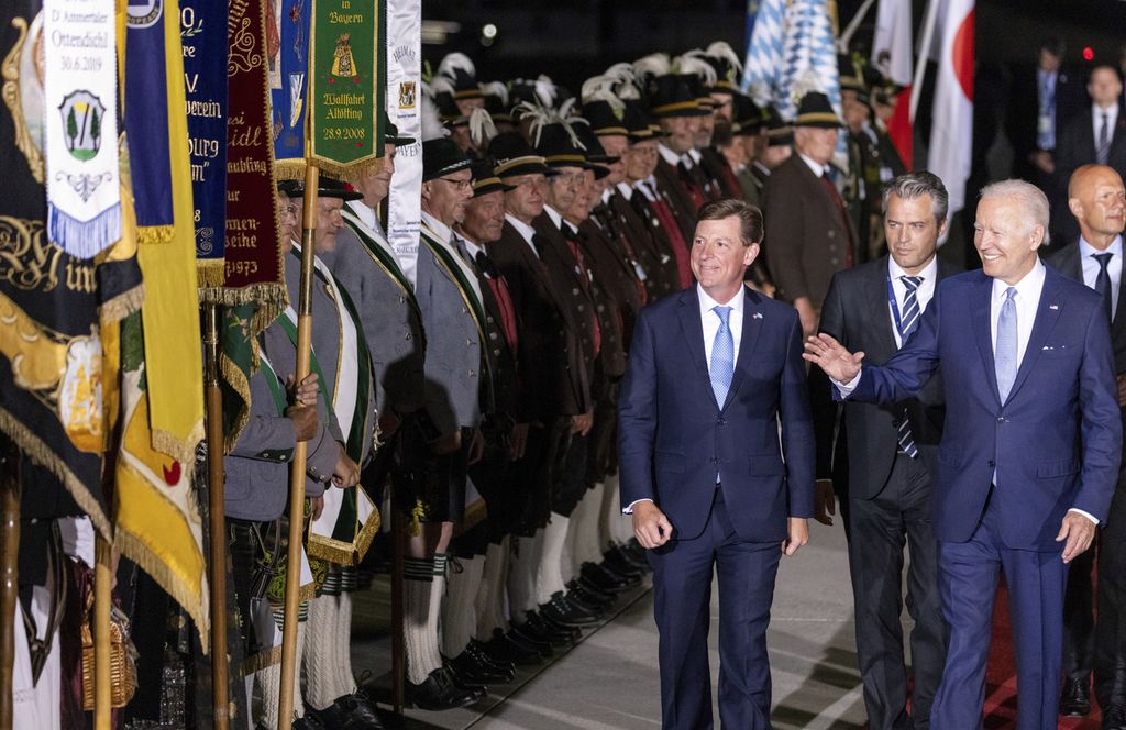 Presiden AS Joe Biden (kanan, depan) melambaikan tangan saat berjalan melewati barisan pasukan tembak Bavaria dan warga yang memakai baju tradisional Bavaria di Bandar Udara Franz-Josef-Strauss, dekat Muenchen, Jerman, Sabtu (25/6/2022), menjelang KTT G7. 