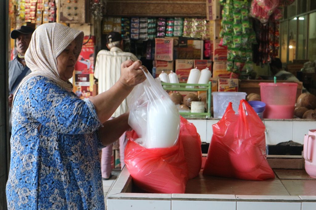Pedagang membungkus dagangannya dengan dua bungkus kantong plastik di Pasar Pos Pengumben, Jakarta Barat, Selasa (4/10/2022).