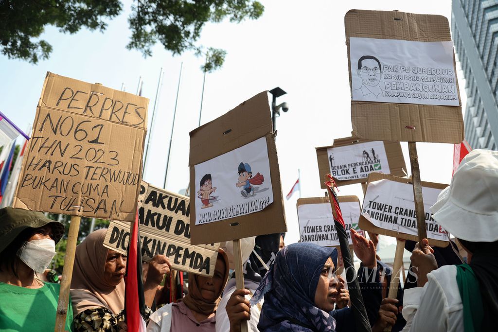Demonstran membawa poster berisi tuntutan mereka saat aksi di depan Balai Kota DKI Jakarta, Senin (11/12/2023).