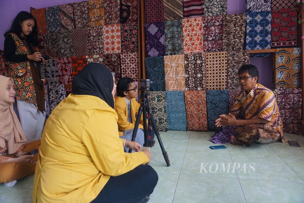 Mahasiswa dan mahasiswi Universitas Jenderal Soedirman Purwokerto sedang berbincang dan membuat konten Youtube dengan pemilik Rumah Batik R Heru Santoso di Sokaraja, Banyumas, Jawa Tengah, Kamis (27/10/2022).