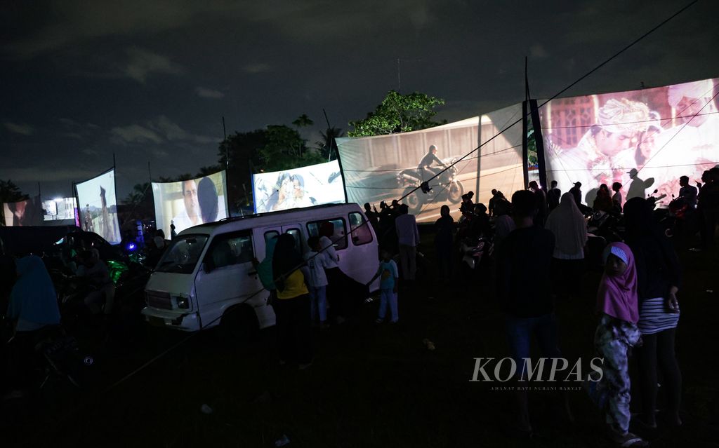 Keramaian di tengah lapangan yang memutar 21 film layar tancap secara bersamaan dalam festival layar tancap di Babakan, Kecamatan Setu, Tangerang Selatan, Banten, Rabu (18/1/2023) malam. 