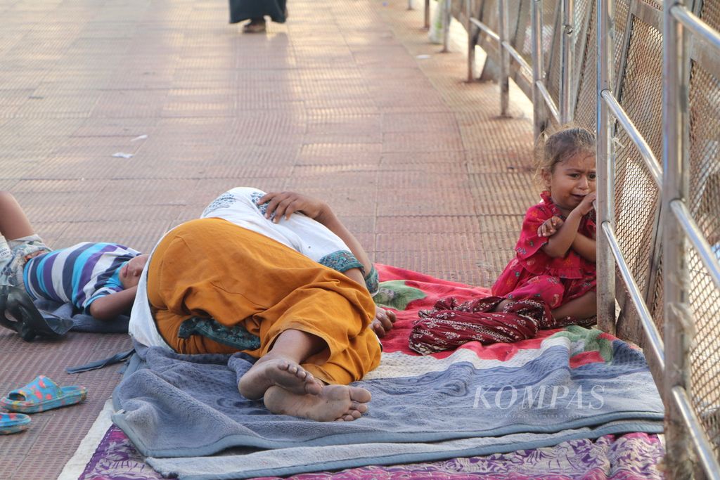 Seorang anak menangis di dekat ibunya yang tertidur di jembatan penyeberangan orang di kota Mumbai, India, Selasa (26/9/2023).