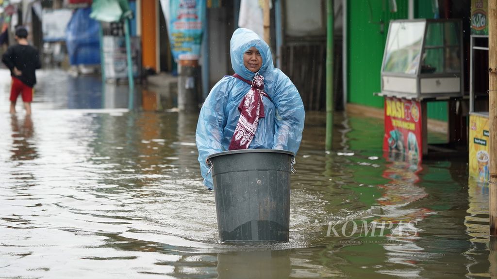 Seorang perempuan menggendong anak sembari membawa ember menembus banjir yang merendam Vila Kencana Cikarang di Desa Karangsentosa, Kecamatan Karangbahagia, Kabupaten Bekasi, Jawa Barat, Kamis (2/3/2023). 