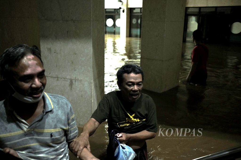 Warga memasuki Masjid Jami Ittihadul Ikhwan saat area sekitar Kelurahan Kampung Melayu, Jatinegara, Jakarta Timur, tergenang banjir pada Senin (7/2/2021).