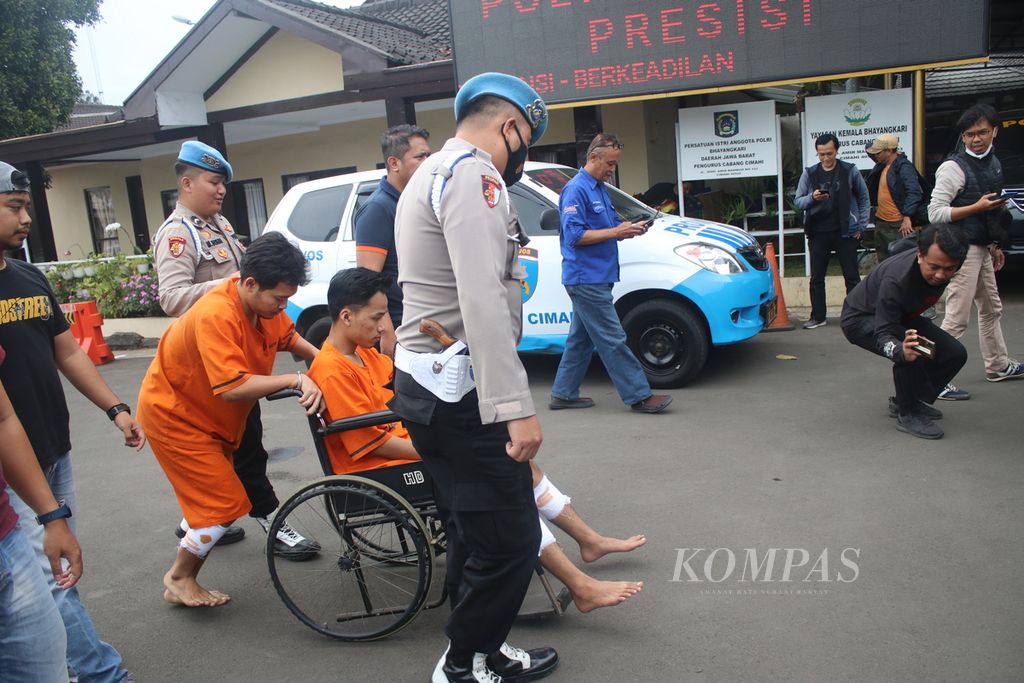 GS (kursi roda) dan AB digiring sejumlah polisi di Markas Kepolisian Resor Cimahi, Jawa Barat, Rabu (8/2/2023). Mereka berdua ditangkap karena melakukan penganiayaan dan ditembak petugas karena dianggap melakukan perlawanan.