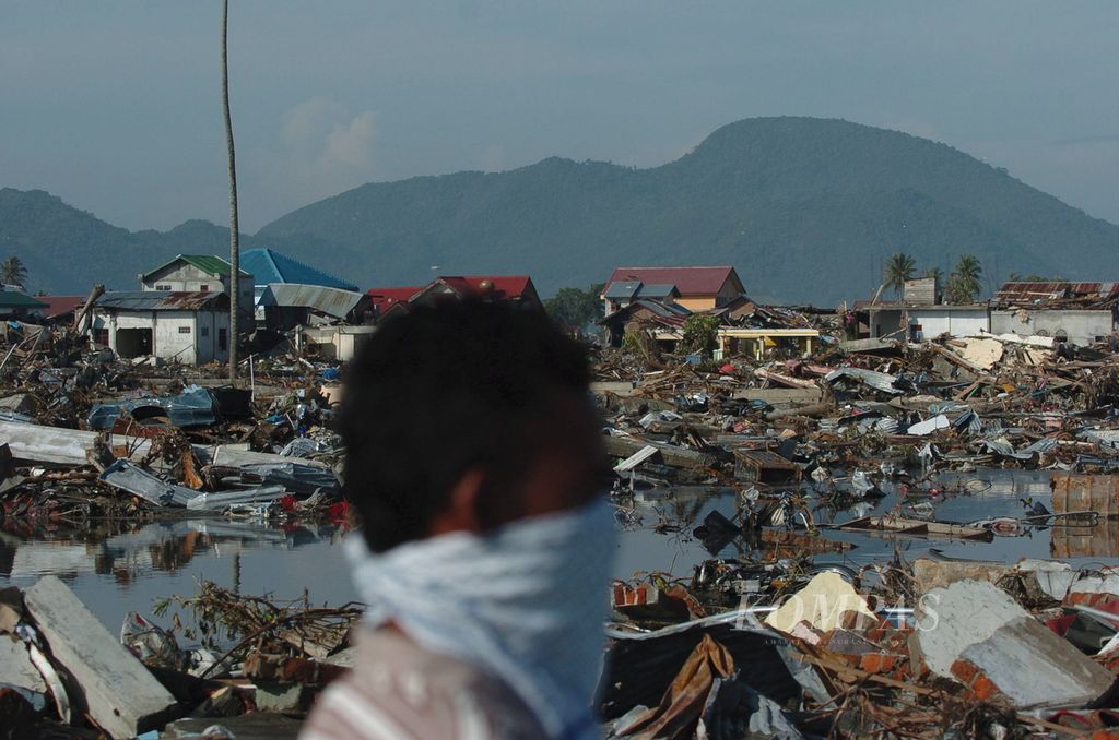 Warga melintas di permukiman yang hancur tersapu gempa dan tsunami di Lampare Kota, Banda Aceh, Selasa (28/12/2004).