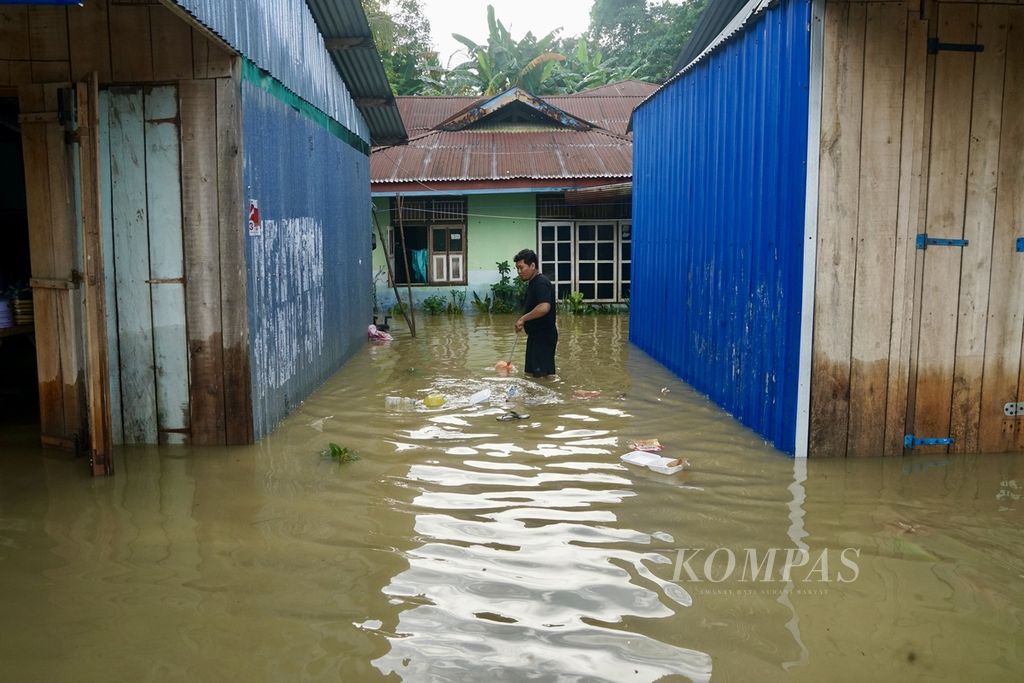 Seorang warga mengeluarkan sampah yang terbawa banjir di kawasan Pasar Panjang, Kendari, Sulawesi Tenggara, Senin (4/3/2024).
