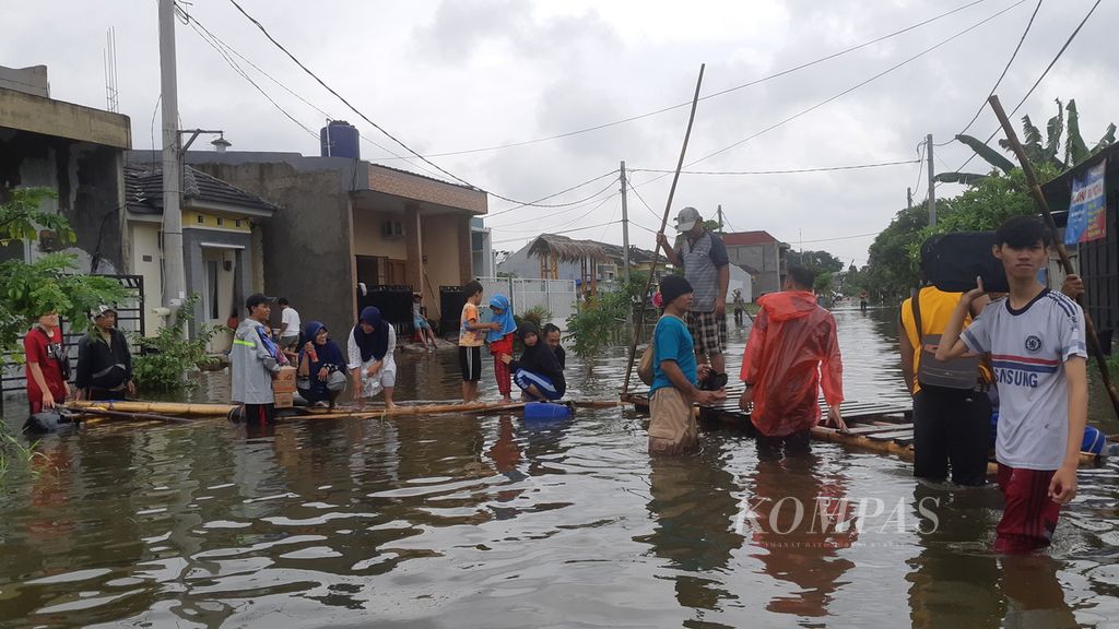 Warga Perumahan Garden City Residence, Periuk, Kota Tangerang, Banten, menggunakan eretan untuk distribusi logistik dan evakuasi warga, Selasa (4/2/2020). Perumahan ini merupakan salah satu lokasi yang terendam banjir sejak Sabtu (1/2/2020) di Kota Tangerang.