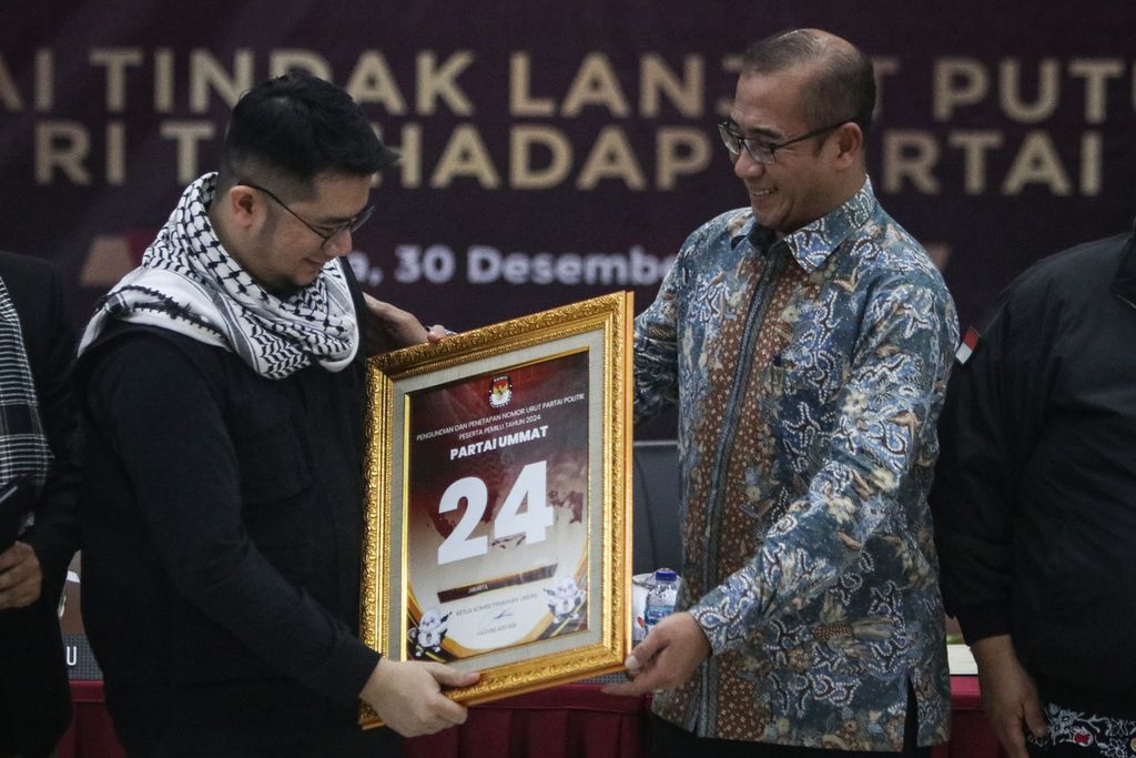 Ketua KPU Hasyim Asy'ari (kanan) memberikan plakat nomor urut partai politik peserta Pemilu 2024 kepada Ketua Umum Partai Ummat Ridho Rahmadi di kantor KPU, Jakarta, Jumat (30/12/2022). 