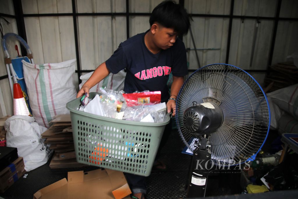 Gilang, penjaga kios Waste Station Rekosistem, memilah sampah yang dikumpulkan warga di kawasan Stasiun MRT Blok M, Jakarta, Rabu (27/7/2022). 