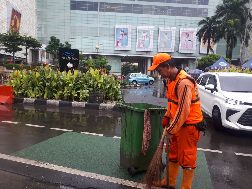 Petugas kebersihan sedang membersihkan jalan dari sampah di area Plaza Indonesia, Jakarta Pusat, Minggu (1/1/2023).
