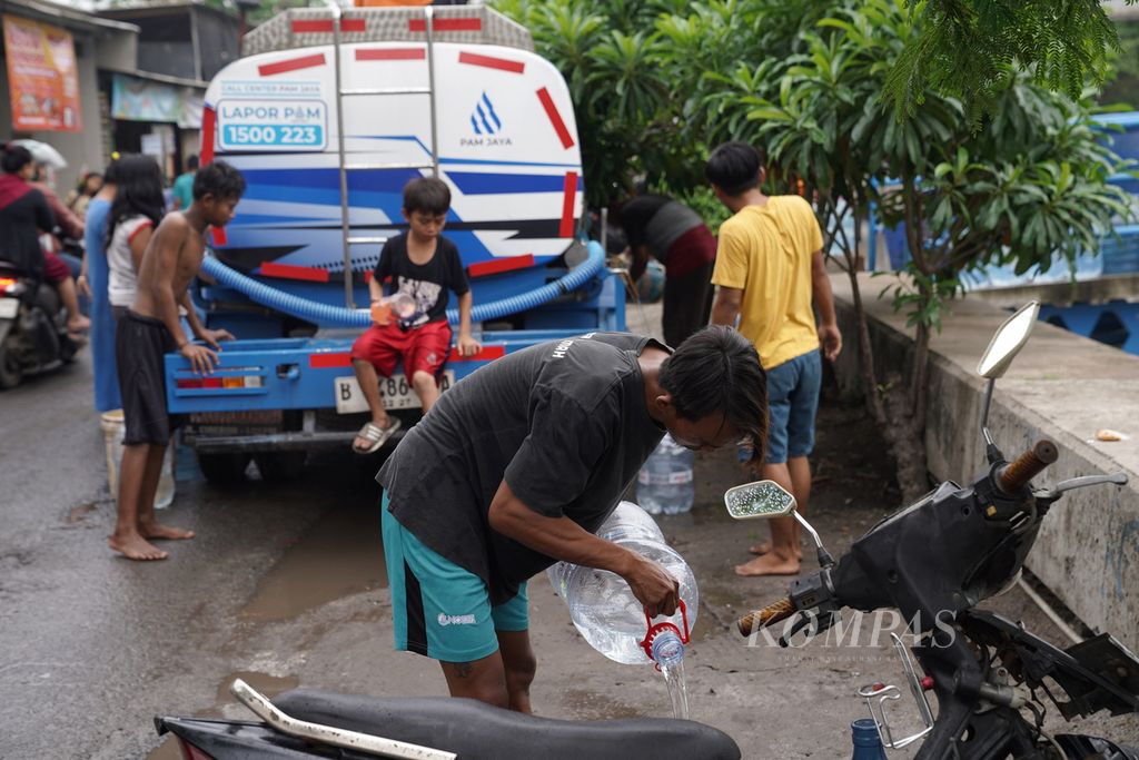 Residents are transferring clean water from a tanker truck into water jugs in Gang Bulak Cabe, RT 006 RW 009, Cilincing Subdistrict, North Jakarta, on Friday (1/12/2023).