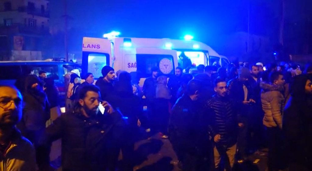 Foto yang diambil dari cuplikan video AFP TV pada 6 Februari 2023 menunjukkan orang-orang berdiri di dekat ambulans saat tim penyelamat berupaya mencari dan menyelamatkan korban gempa di Diyarbakir, tenggara Turki. Gempa bermagnitudo 7,8 mengguncang wilayah itu dan menewaskan lebih dari 100 orang. 