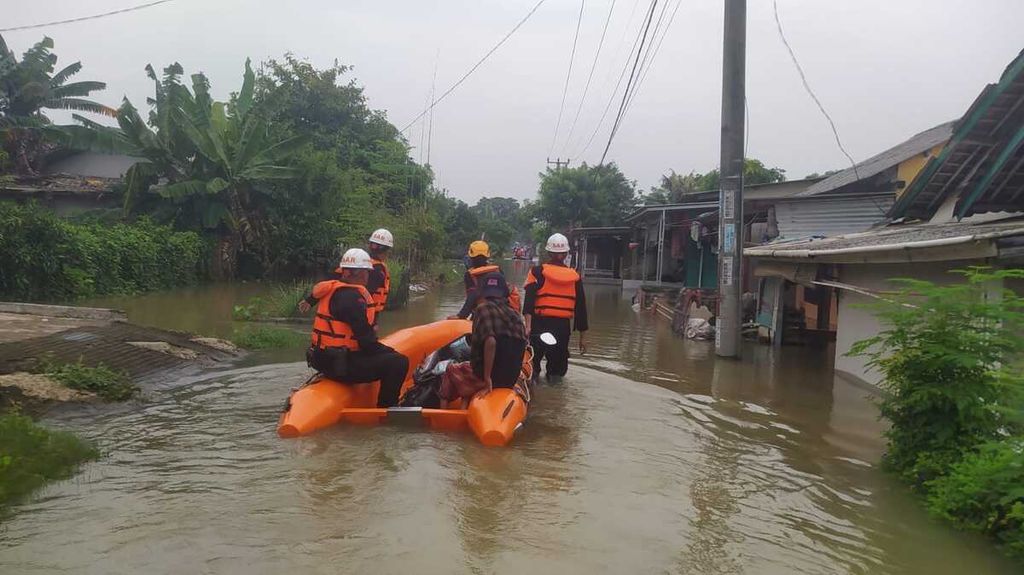 Tampak petugas dari Badan Penanggulangan Bencana Daerah (BPBD) tengah melaksanakan upaya evakuasi warga di lokasi yang terdampak banjir di Kabupaten Karawang, Jawa Barat, Minggu (7/1/2024). Sebanyak 2.298 warga terdampak banjir di Karawang.