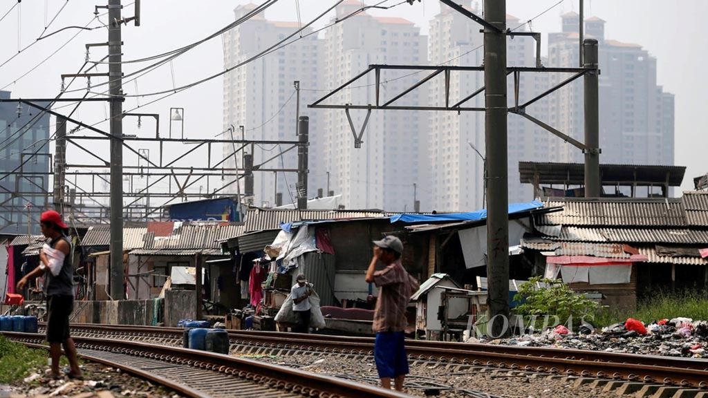 Dwellers of semi-permanent buildings along the railway tracks in Kampung Bandan area, North Jakart, with the background of multi-storied residential buildings on Tuesday (23/5). The poverty rate per September 2016 reached 27.76 million people, or 10.70 percent of the total population. This year, the government targets the poverty will decline to 10.5 percent. To accelerate reduction in the economic inequality pace, the government will raise and empower 40 percent of the poor population.