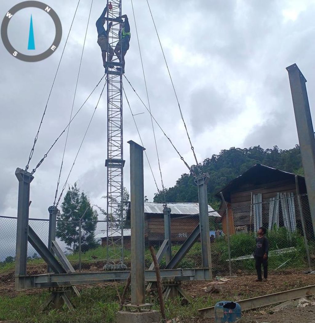 Para pekerja PT Infrastruktur Bisnis Sejahtera sedang membangun salah satu menara <i>base transceiver station</i> (BTS) sepanjang 18 meter di wilayah pedalaman Papua tahun 2022.