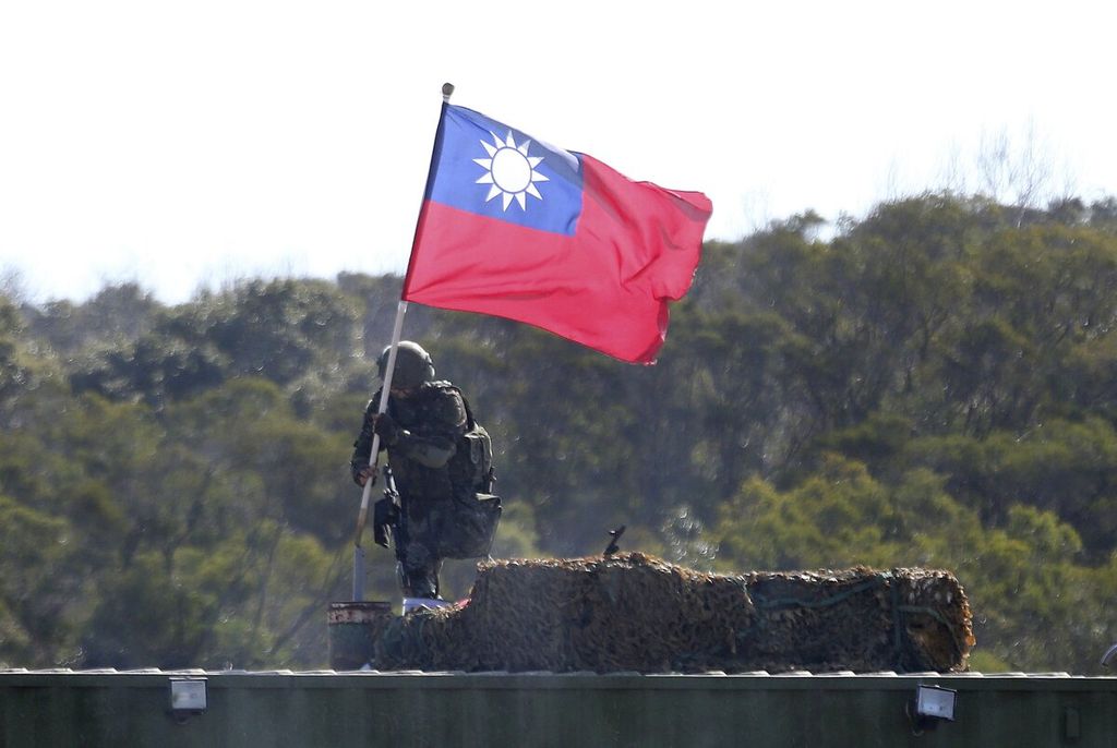Seorang tentara memegang bendera nasional Taiwan dalam latihan di Hsinchu, Taiwan. Presiden Taiwan Tsai Ing-wen berusaha meningkatkan kemampuan pertahanan Taiwan dengan pembelian senjata senilai miliaran dollar AS dari sekutu utama AS, termasuk jet tempur F-16. 