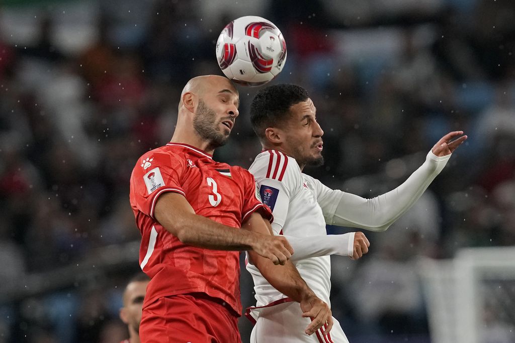 Pemain Palestina, Mohammed Rashid (kiri), berebut bola dengan pemain Uni Emirat Arab, Ali Saleh Amro, pada laga Grup C Piala Asia 2023 di Stadion Al Janoub, Al Wakrah, Qatar, Kamis (18/1/2024). Laga yang diwarnai rintik hujan itu berakhir imbang 1-1.