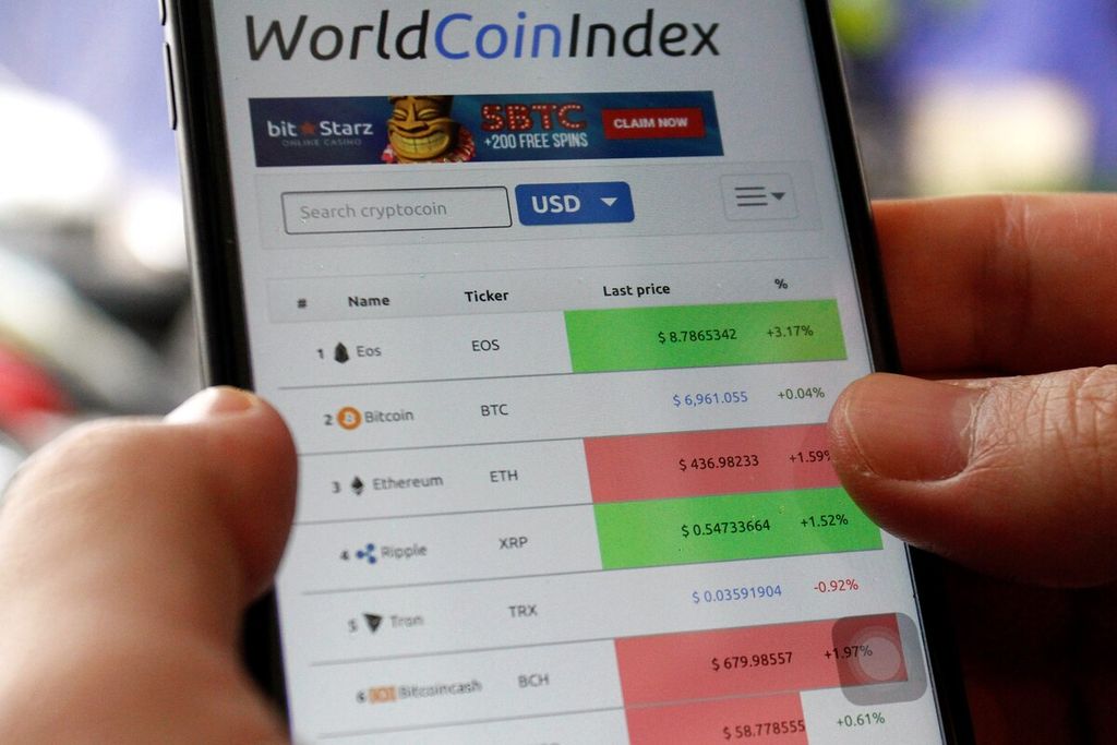 Investor mengecek indeks koin dunia dari telepon selulernya, April 2018.