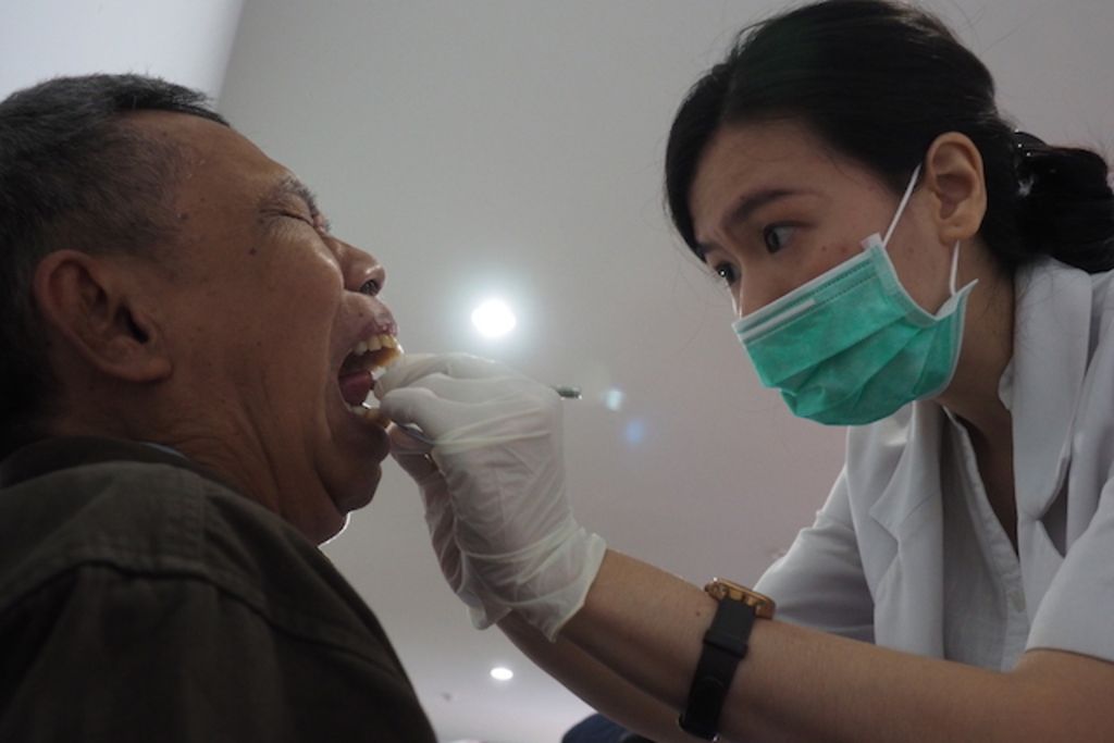 Seorang dokter gigi memeriksa kondisi kesehatan gigi dan mulut dalam program pengabdian masyarakat di Puskesmas Kecamatan Kramat Jati, Jakarta.